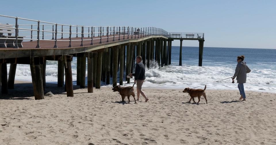 People walk their dogs near Ocean Grove's cross-shaped pier Monday, April 10, 2023. as work continues to finish the project.  The pier is scheduled to open to the public on April 15.  