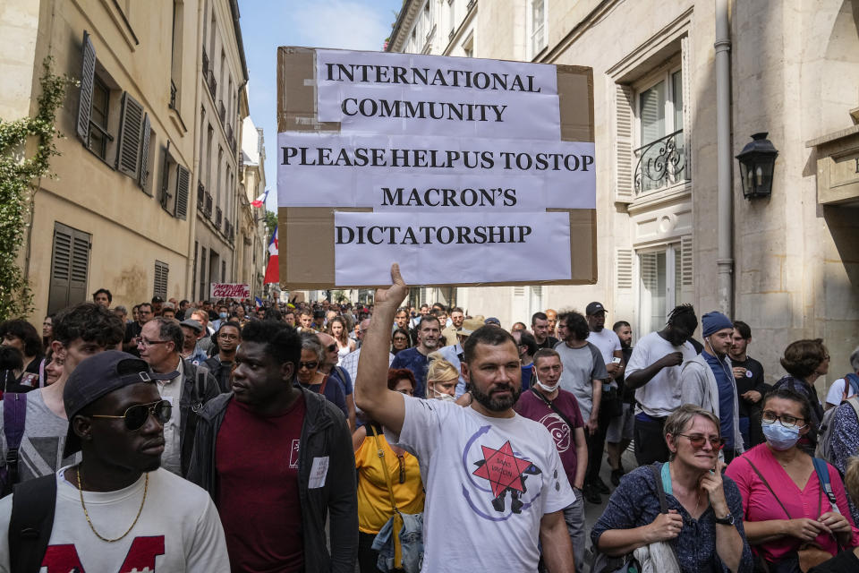 Anti-vaccine protester holds a placard during a rally in Paris, Saturday, July 17, 2021. Tens of thousands of people protested across France on Saturday against the government's latest measures to curb rising COVID-19 infections and drive up vaccinations in the country. (AP Photo/Michel Euler)