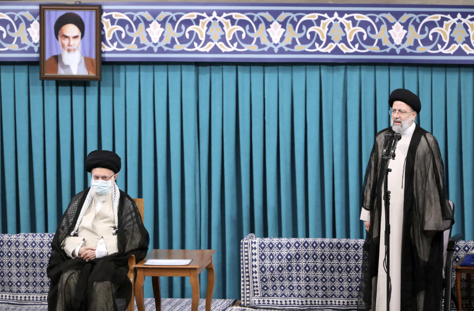 In this photo released by an official website of the office of the Iranian supreme leader, newly elected President Ebrahim Raisi, right, speaks after receiving official seal of approval of Supreme Leader Ayatollah Ali Khamenei, left, in an endorsement ceremony in Tehran, Iran, Tuesday, Aug. 3, 2021. A portrait of the late revolutionary founder Ayatollah Khomeini hangs at top left. (Office of the Iranian Supreme Leader via AP)