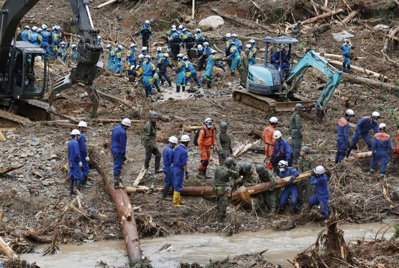 Rescue workers search for missing people at a landslide site caused by torrential rain in Tsunagi town