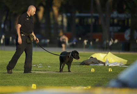 A law enforcement officer uses a police dog to search for evidence at the scene where a man set himself on fire within sight of the U.S. Capitol building on the U.S. National Mall in Washington, October 4, 2013. REUTERS/Gary Cameron