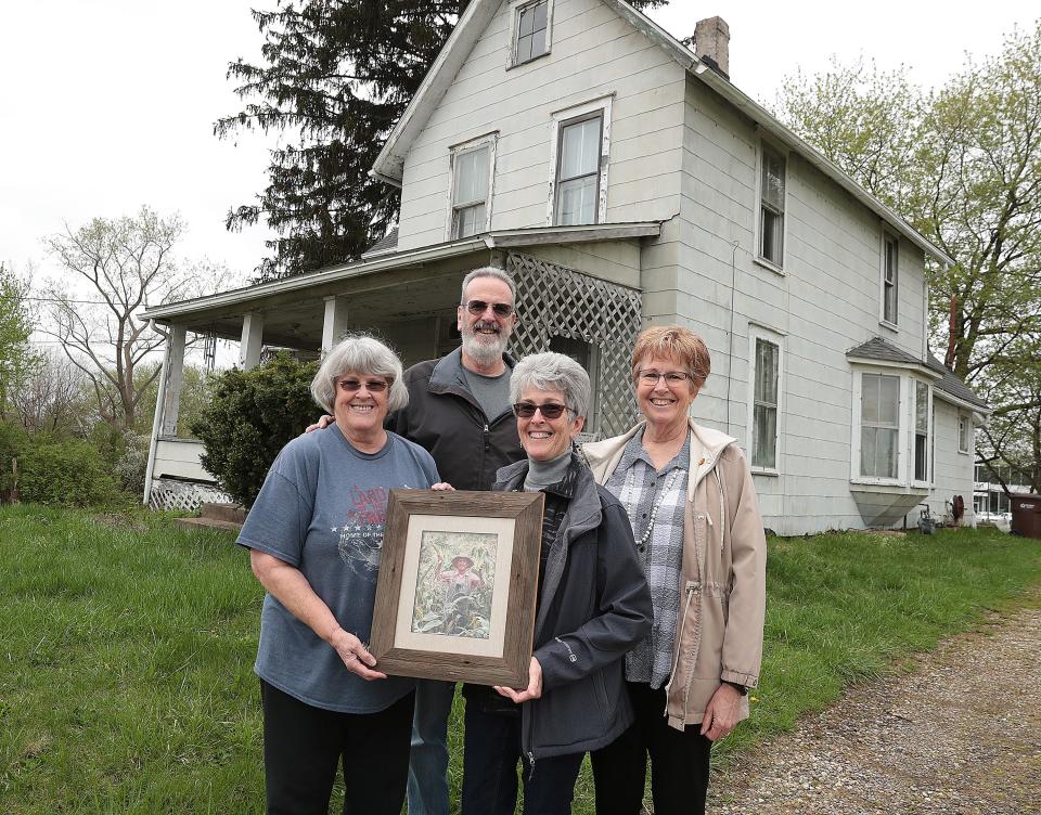 Siblings (from left) Vivian Floom, Greg Floom, Barbie Ream, and Debbie Sprit pose with a photo of their father in front of their Jackson Township farmhouse they grew up in along with 5 other siblings.