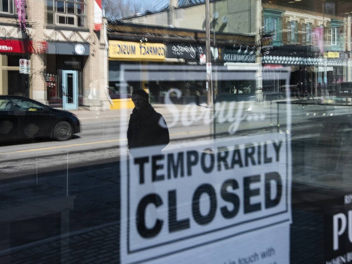 Storefronts in Ottawa's Glebe neighbourhood are reflected in a window sign on March 24, 2020, during the COVID-19 pandemic. (Justin Tang/The Canadian Press - image credit)