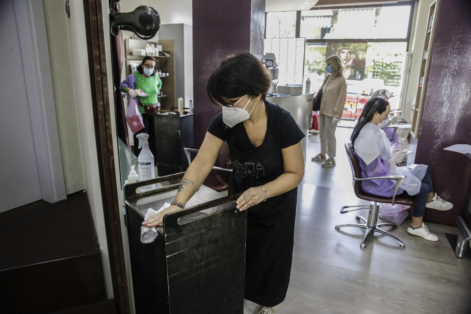 Hairdresser Piera Delogu cleans her hairstyling shop, in Milan, Italy, Monday 18, May 15, 2020. Italy is slowly easing its strict sanitary measures against the spread of coronavirus. (AP Photo/Luca Bruno)