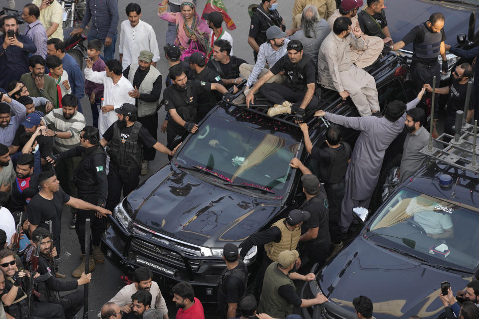 Security personnels and supporters move with a vehicle, center, carrying Pakistan's former Prime Minister Imran Khan during an election campaign rally, in Lahore, Pakistan, Monday, March 13, 2023. Khan rallied thousands of supporters in eastern Pakistan on Monday as courts in the capital, Islamabad, issued two more arrest warrants for him over his failure to appear before judges in graft and terrorism cases, officials said. (AP Photo/K.M. Chaudary)