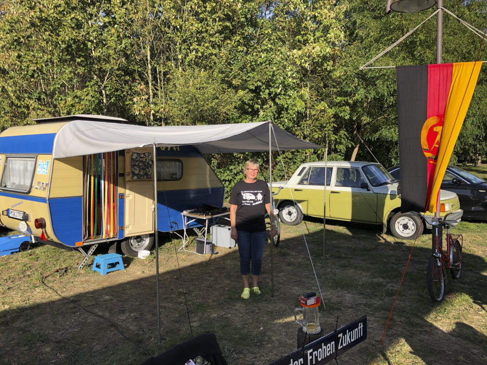 Kerstin Ade poses for a photo in front of a historic camper and a former East German Wartburg car, during a meeting of campers in Leipzig, Germany, Saturday, Sept. 17, 2020. It’s been three decades since the reunification Germany, but twice a year camping enthusiasts from the former east allow themselves to forget about how much has changed and relive times past. (AP Photo/Kerstin Sopke)