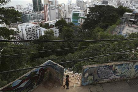 A boy walks next to a slope where neighbours throw garbage at the Cantagalo slum in Rio de Janeiro March 13, 2014. REUTERS/Pilar Olivares