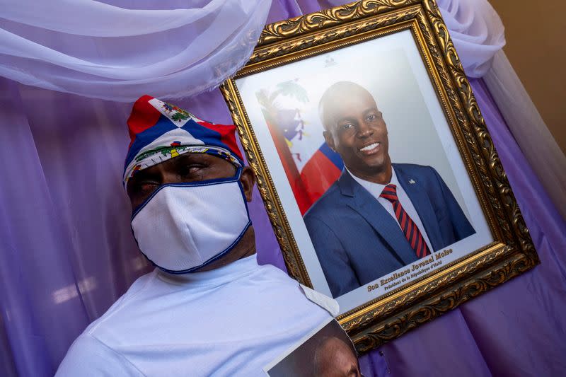 FILE PHOTO: A man stands next to a portrait of slain Haitian President Jovenel Moise placed on a memorial at the city hall in Cap-Haitien
