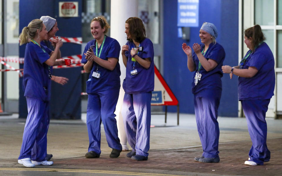 Staff from the Royal Liverpool University Hospital join in a national applause to salute local heroes during the nationwide Clap for Carers NHS initiative to applaud workers fighting the coronavirus pandemic, Thursday, April 2, 2020, in Liverpool, England. The new coronavirus causes mild or moderate symptoms for most people, but for some, especially older adults and people with existing health problems, it can cause more severe illness or death. (Peter Byrne/PA via AP)