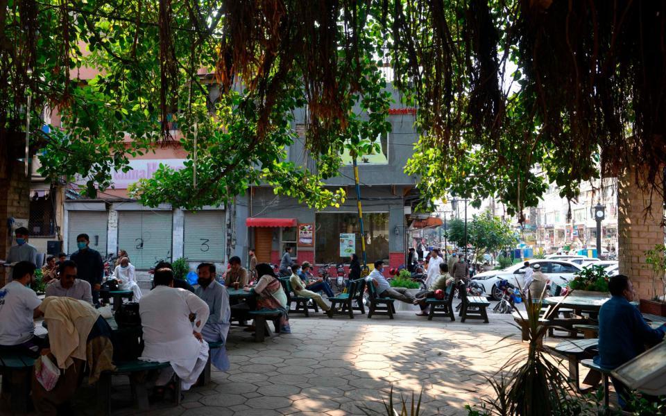 People sit at tables in the Pindi food street market in Rawalpindi as lockdown eases - FAROOQ NAEEM /AFP