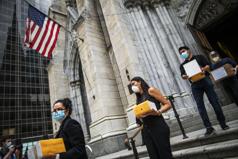 Mourners carry out the remains of loved ones following the blessing of the ashes of Mexicans who died from COVID-19 at St. Patrick's Cathedral, Saturday, July 11, 2020, in New York. The ashes were blessed before they were repatriated to Mexico. (AP Photo/Eduardo Munoz Alvarez)