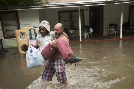 Charles Davidson helps his neighbor Santonio Coleman, 11, from his flooded home in the Kelly Ave. Basin area of Pensacola, Florida, April 30, 2014. REUTERS/Michael Spooneybarger