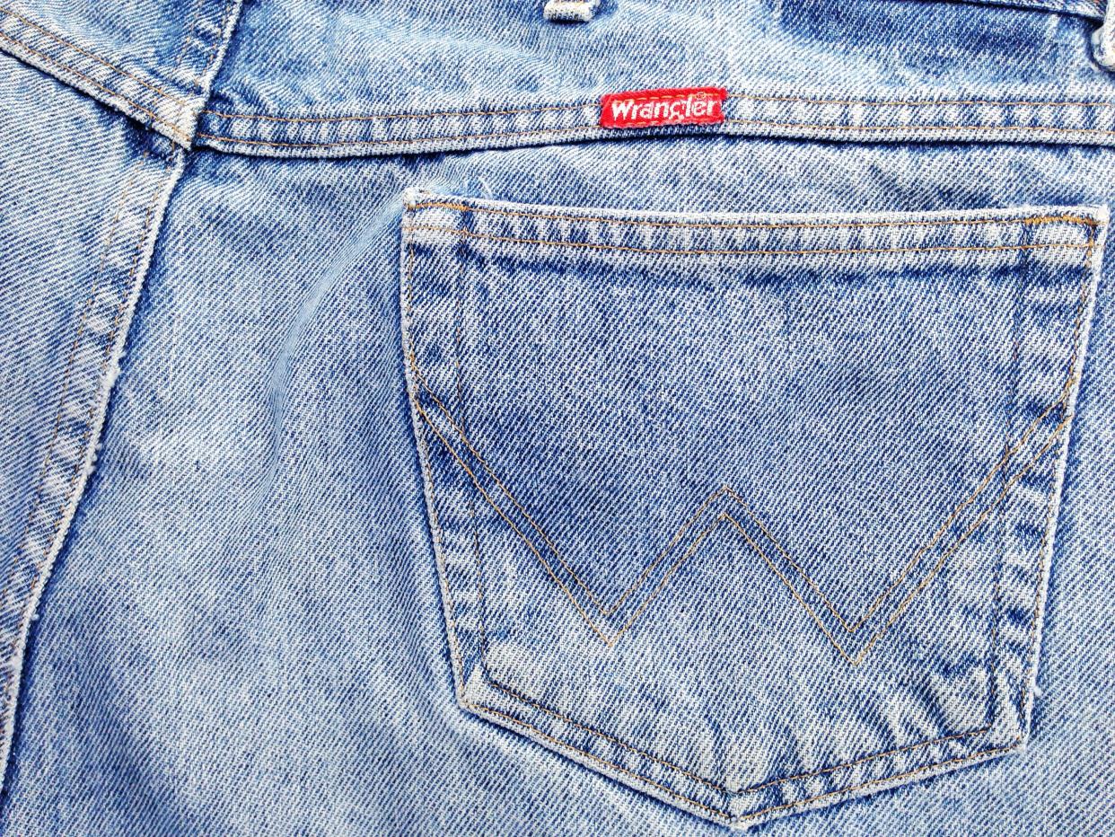 Closeup of red Wrangler brand name label on the back pocket of a pair of worn Wrangler jeans