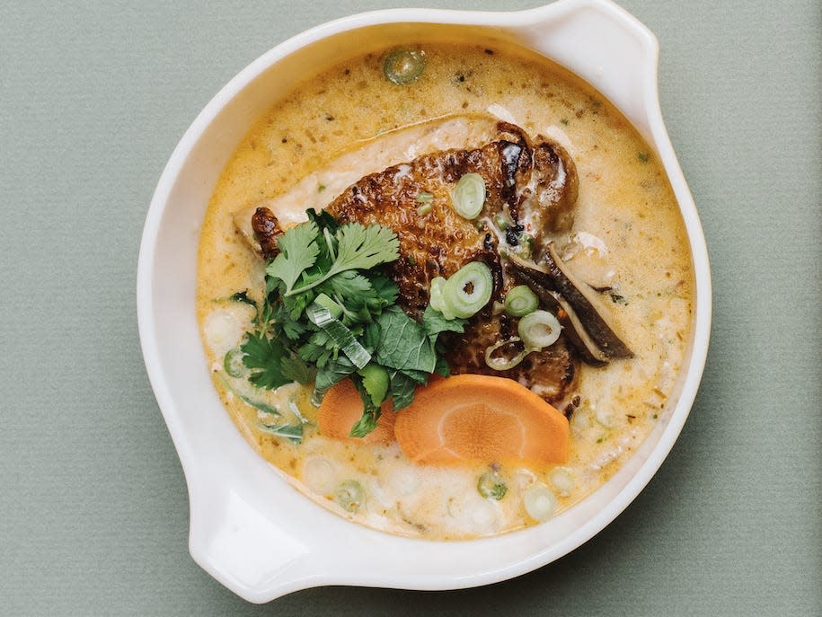 thai chicken soup in a white bowl on a grey background