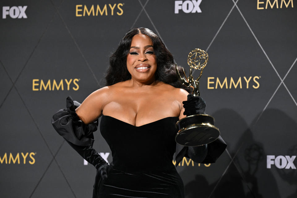 Closeup of Niecy Nash holding her Emmy award