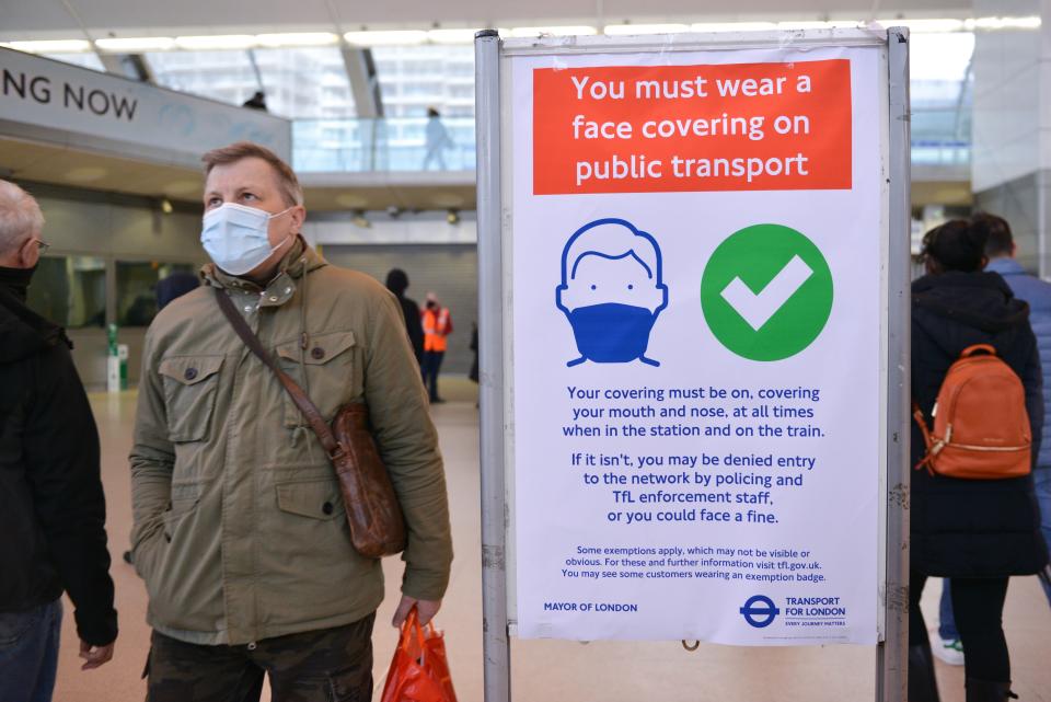 LONDON, UNITED KINGDOM - 2021/12/06: A commuter seen walking past a Wear Face Covering poster at Stratford Station.
Face coverings in England have become compulsory again in public transport, in fear of the new Covid-19 variant, Omicron. (Photo by Thomas Krych/SOPA Images/LightRocket via Getty Images)