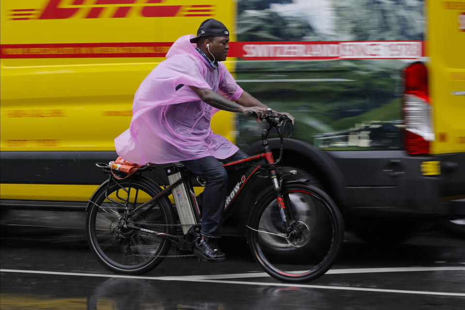 A cyclist uses a plastic rain cover to protect themselves from rain brought about by Tropical Storm Fay Friday, July 10, 2020, in New York. Beaches closed in Delaware and rain lashed the New Jersey shore as fast-moving Tropical Storm Fay churned north on a path expected to soak the New York City region. (AP Photo/Frank Franklin II)