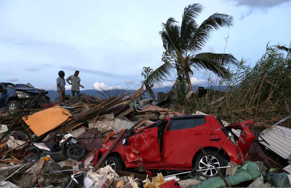 In this Oct. 7, 2018, file photo, men chat on top of the rubble at Petobo neighborhood, which was wiped out by the earthquake-triggered tsunami, in Palu, Central Sulawesi, Indonesia,. (AP Photo/Dita Alangkara, File)