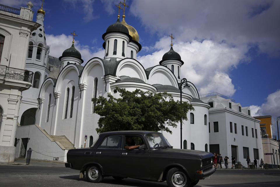 A vintage Russian-made Lada car passes the Russian Our Lady of Kazan Orthodox Cathedral in Havana, Cuba, Friday, April 1, 2022. Global restrictions on transport and trade with Russia after its invasion of Ukraine pose a serious problem for Cubans because much of the island's fleets of trucks, buses, cars and tractors came from distant Russia and are now aging and in need of parts. (AP Photo/Ramon Espinosa)