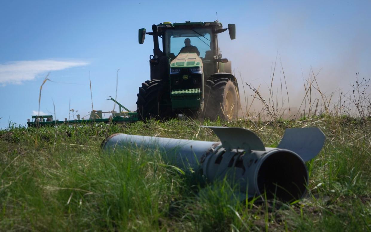 A fragment of a Russian missile is seen as a farmer works on his field in Izium, Kharkiv region, Ukraine