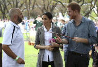 Britain's Prince Harry and Meghan, Duchess of Sussex are shown a boomerang during a visit to a community picnic at Victoria Park in Dubbo, Australia, Wednesday, Oct. 17, 2018. Prince Harry and his wife Meghan are on day two of their 16-day tour of Australia and the South Pacific. (Ian Vogler/Pool via AP)