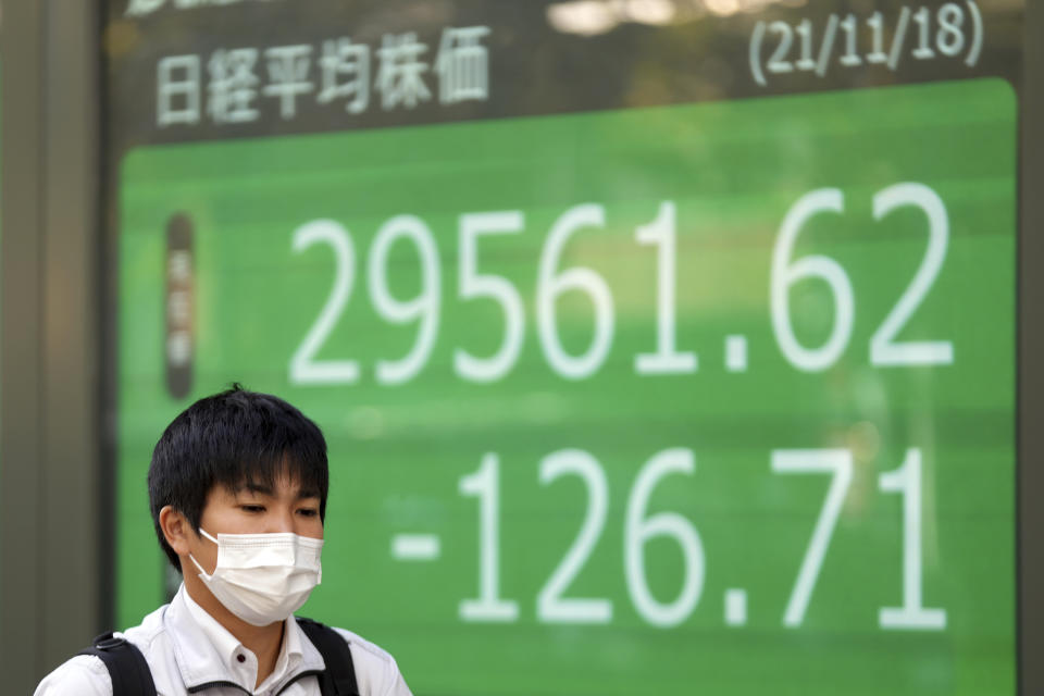 A man wearing a protective mask walks near an electronic stock board showing Japan's Nikkei 225 index at a securities firm Thursday, Nov. 18, 2021, in Tokyo. Asian shares mostly declined Thursday after stock indexes shuffled lower on Wall Street. (AP Photo/Eugene Hoshiko)