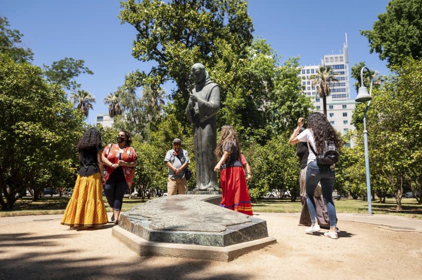 In this June 16, 2020, photo, people gather near the Father Junipero Serra statue on the Capitol Park grounds in Sacramento, Calif. More than a year after protesters toppled the statue of the Spanish missionary on the grounds of the California Capitol, Gov. Gavin Newsom signed a law on Friday, Sept. 24, 2021, to replace it with a memorial for the state's Native people. The statue of Father Junipero Serra had stood in Capitol Park since 1967. (Xavier Mascarenas/The Sacramento Bee via AP, File)