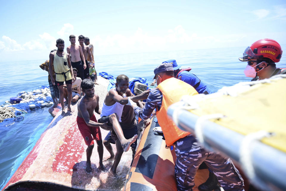 Rohingya refugees climb onto a National Search and Rescue Agency boat as they are being rescued after their boat capsized in the waters off West Aceh, Indonesia, Thursday, March 21, 2024. The wooden boat carrying dozens of Rohingya Muslims capsized off Indonesia's northernmost coast on Wednesday, according to local fishermen. (AP Photo/Reza Saifullah)