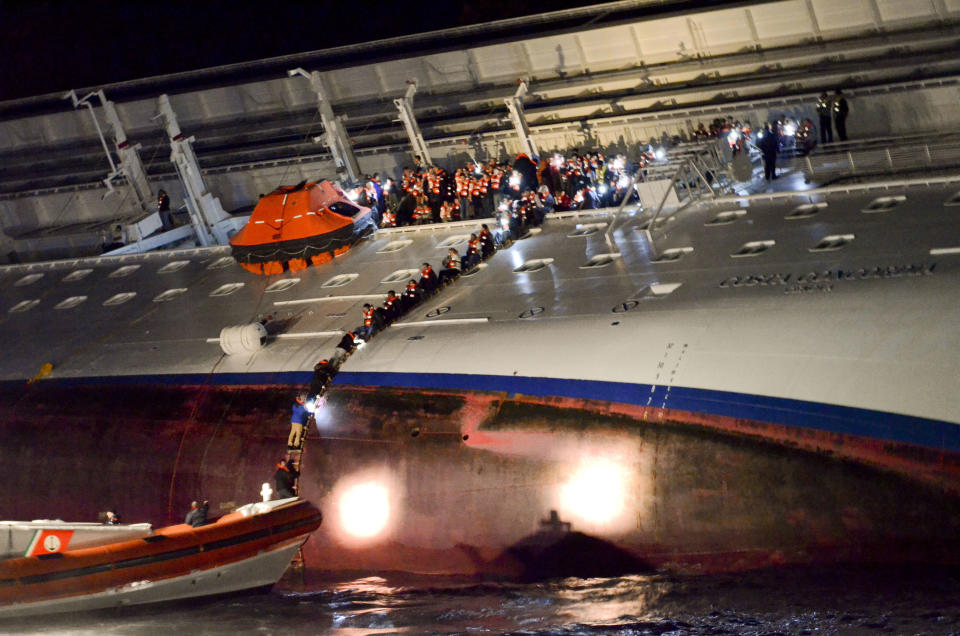 In this photo released by the Corriere Fiorentino newspaper Friday, March 2, 2012, and taken on Jan. 13, 2012, unidentified people abandon the Costa Concordia cruise ship laying on its starboard side after it ran aground off the coast of the Isola del Giglio island, Italy, gashing open the hull and forcing some 4,200 people aboard to evacuate aboard lifeboats to the nearby Isola del Giglio island. The first hearing to discuss evidence for the accident in which the Costa Concordia crashed, killing 32 people, will take place Saturday Feb. 3, 2012,  in Grosseto, Italy.  (AP Photo/Corriere Fiorentino) ITALY OUT