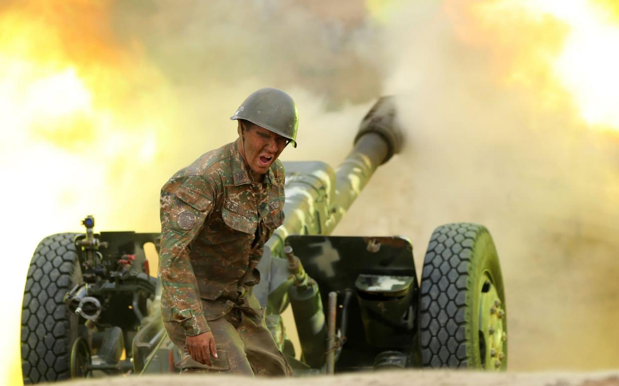 A solider in Karabakh's army fires artillery rounds towards an Azerbaijani position on September 28 - AFP