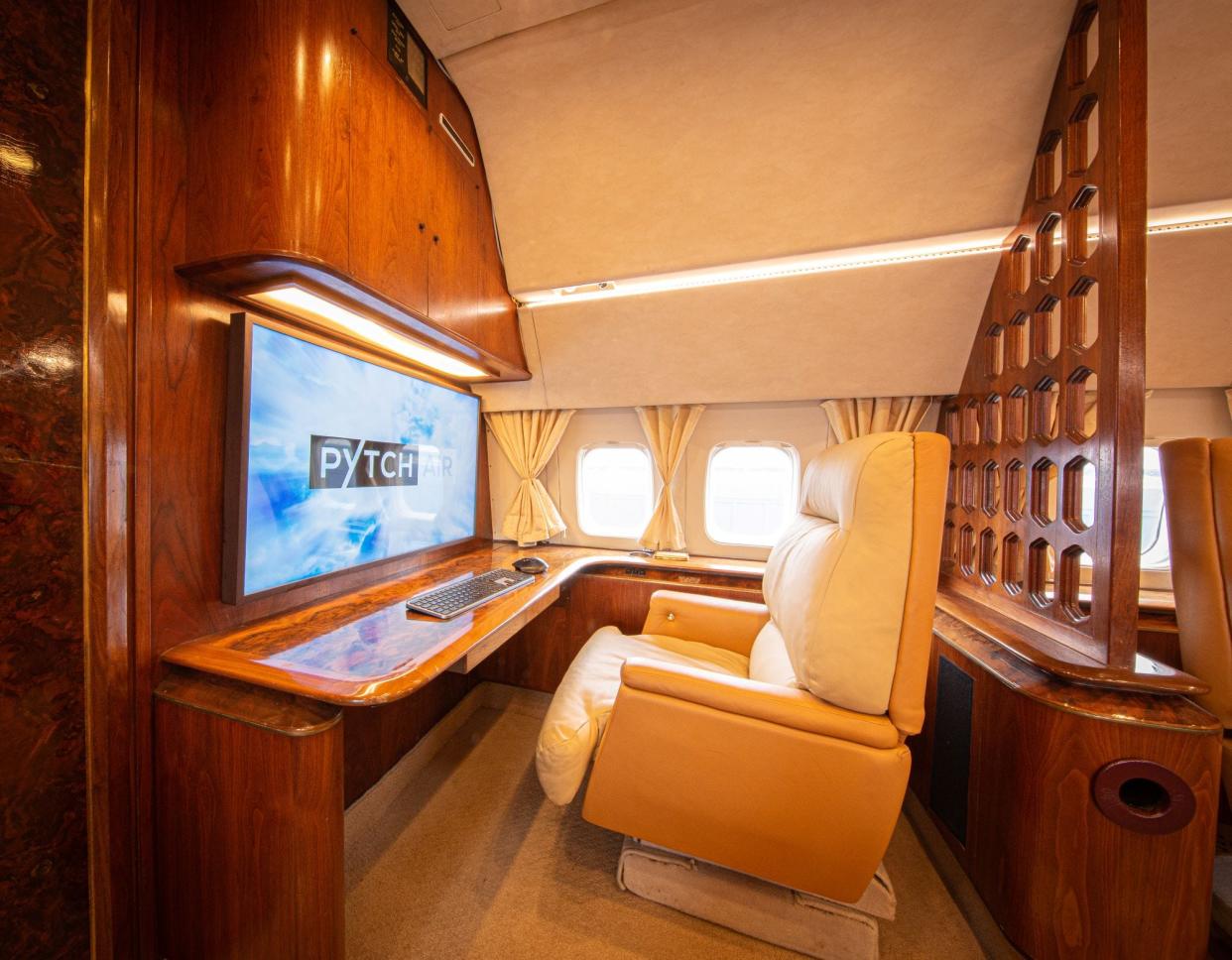 Beige armchair facing computer in private jet.