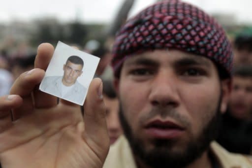 A Syrian anti-regime protester holds a picture of a disappeared relative as they gather around UN observers in the village of Azzara on May 4. Syrians voted on Monday in the country's first "multiparty" parliamentary election in five decades, held against a backdrop of violence and dismissed as a sham by the opposition