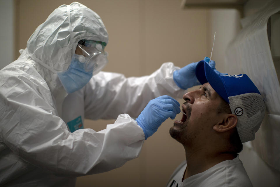 ARCHIVO - En esta imagen del 14 de julio de 2020, una trabajadora sanitaria toma una muestra para una prueba PCR de COVID-19 en un hospital local de Hospitalet a las afueras de Barcelona, en España. El virus está repuntando en algunas partes de España, y parece que Cataluña y otras regiones no están adecuadamente preparadas para rastrear los nuevos contagios, lo que se supone debería ser un sistema de detección temprana para frenar los nuevos brotes e impedir una nueva oleada de casos. (AP Photo/Emilio Morenatti, Archivo)