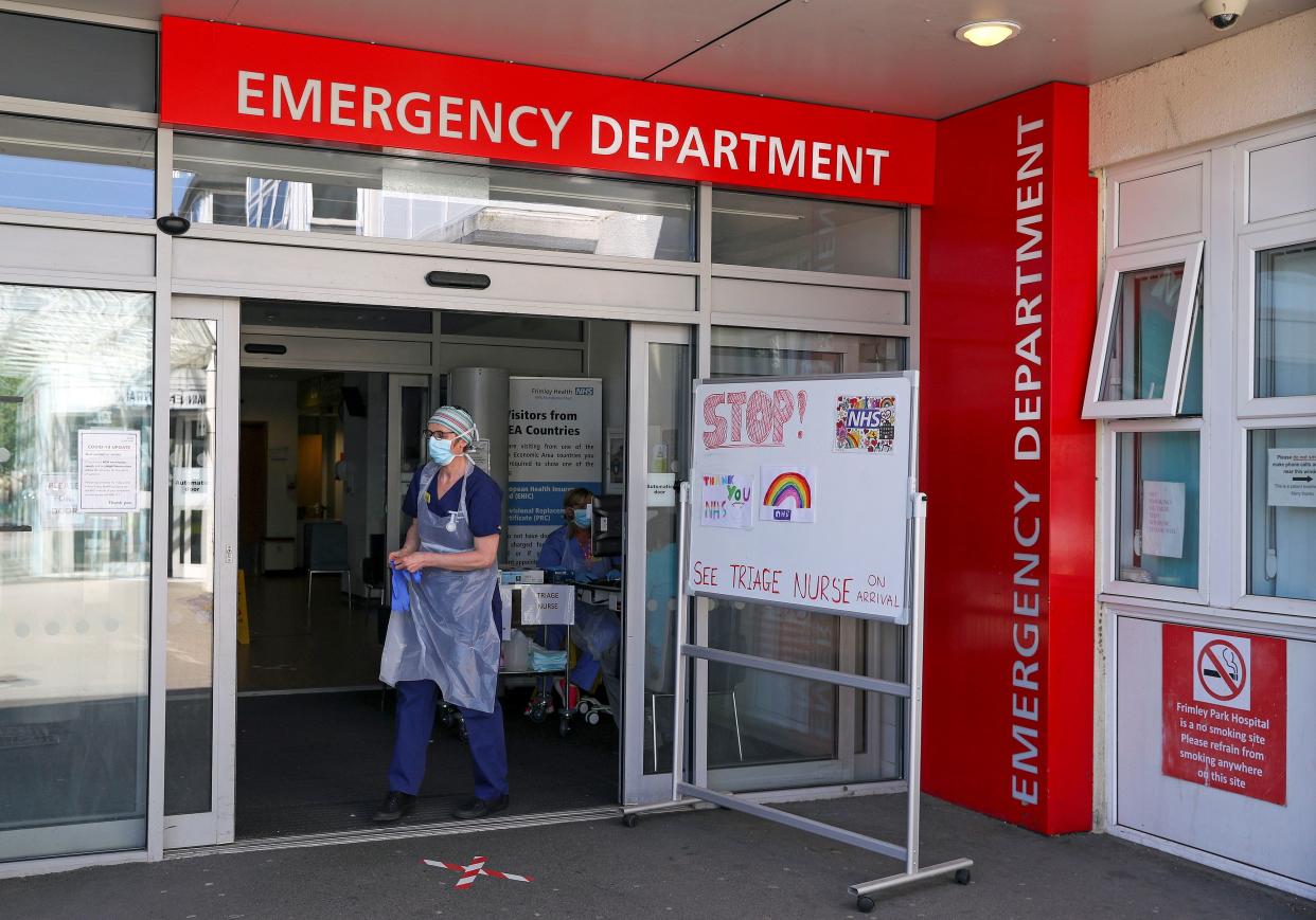 A medical professional wearing PPE (personal protective equipment) including a face mask, and plastic apron as a precautionary measure against COVID-19  waits triage patients at the entrance of the A&E Emergency department, implemented during the COVID-19 pandemic, at Frimley Park Hospital in Frimley, southwest England on May 22, 2020. - Britain's number of deaths "involving" the coronavirus has risen to 46,000, substantially higher than the 36,914 fatalities officially reported so far, according to a statistical update released Tuesday. (Photo by Steve Parsons / POOL / AFP) (Photo by STEVE PARSONS/POOL/AFP via Getty Images)
