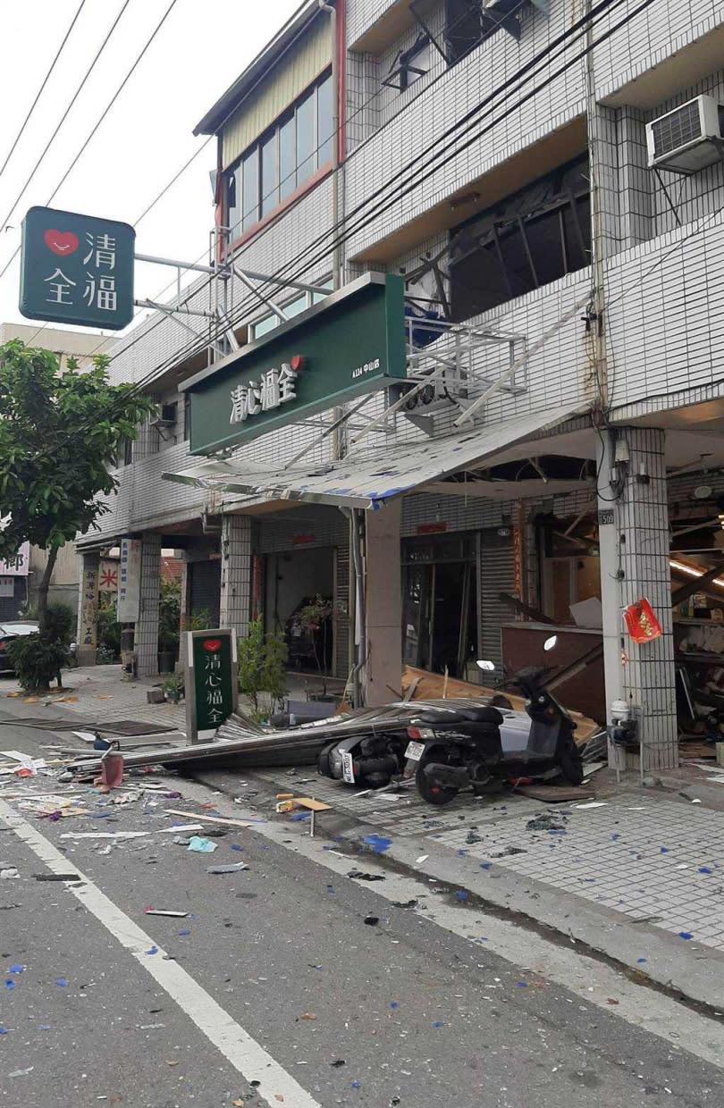 現場一片狼藉，店家停在門口的機車也被掉落下來的鐵皮壓垮，隔壁鄰居家的鐵門及玻璃門，也都承受不了衝擊力道，被擠壓變形。（圖／消防局提供）