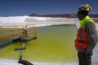 Staff at the Albemarle lithium mine walk along a pool of brine highly concentrated in lithium at Chile's Atacama Desert, Monday, April 17, 2023. (AP Photo/Rodrigo Abd)