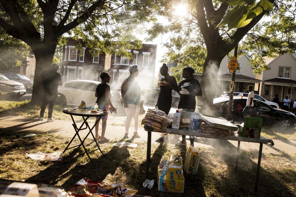 In this Thursday, Aug. 1, 2019, photo, people gather for a barbecue in a vacant lot hosted by Inner-city Muslim Action Network's (IMAN) in Chicago's neighborhood of West Englewood. IMAN seeks to educated people on proper nutrition in a section of the city with low access to nutritional foods. (AP Photo/Amr Alfiky)