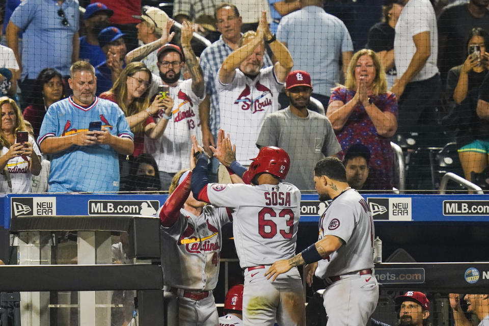 Fans watch as St. Louis Cardinals' Edmundo Sosa (63) celebrates with teammates after scoring on a two-run single by Andrew Knizner during the 11th inning of the team's baseball game against the New York Mets on Tuesday, Sept. 14, 2021, in New York. (AP Photo/Frank Franklin II)