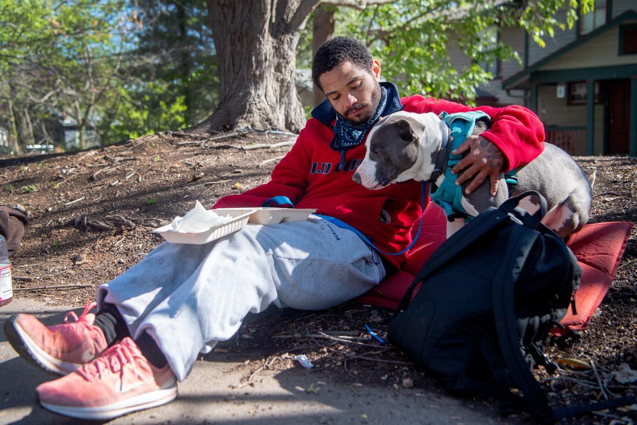 Reginald Bolden Jr. sits with his dog, Smoke, while eating breakfast at ABCCM in Asheville, April 13, 2024.