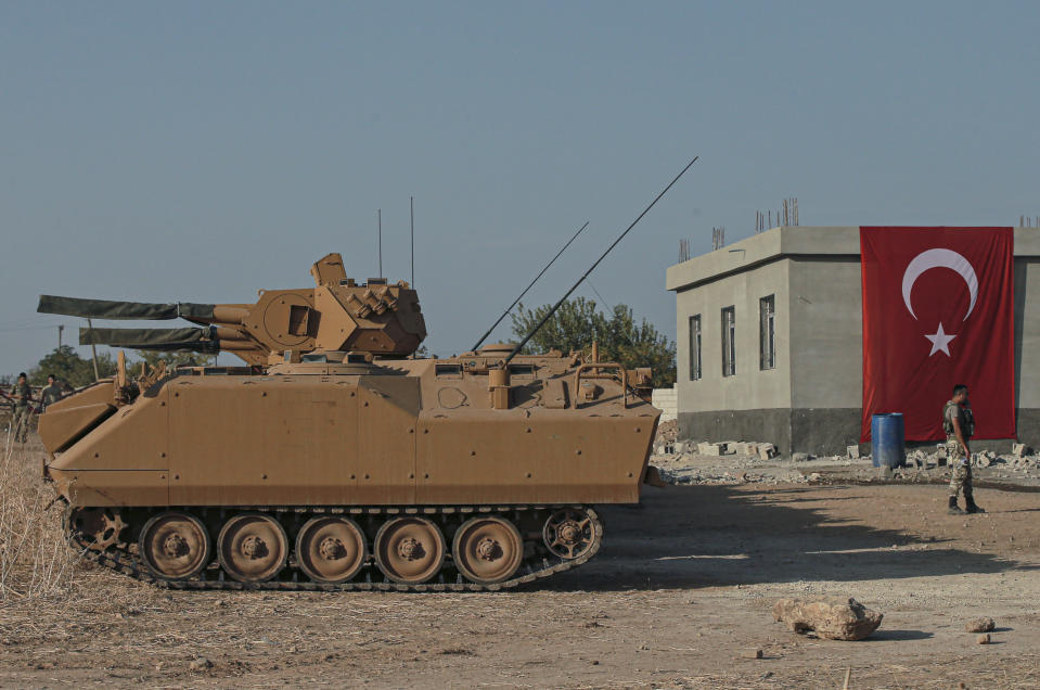 Turkish army personnel carriers are parked on a road towards the border of Syria in Sanliurfa province, Turkey, Monday, Oct. 14, 2019. Syrian troops entered several northern towns and villages Monday, getting close to the Turkish border as Turkey's army and opposition forces backed by Ankara marched south in the same direction, raising concerns of a clash between the two sides as Turkey's invasion of northern Syria entered its sixth day. (AP Photo/Emrah Gurel)