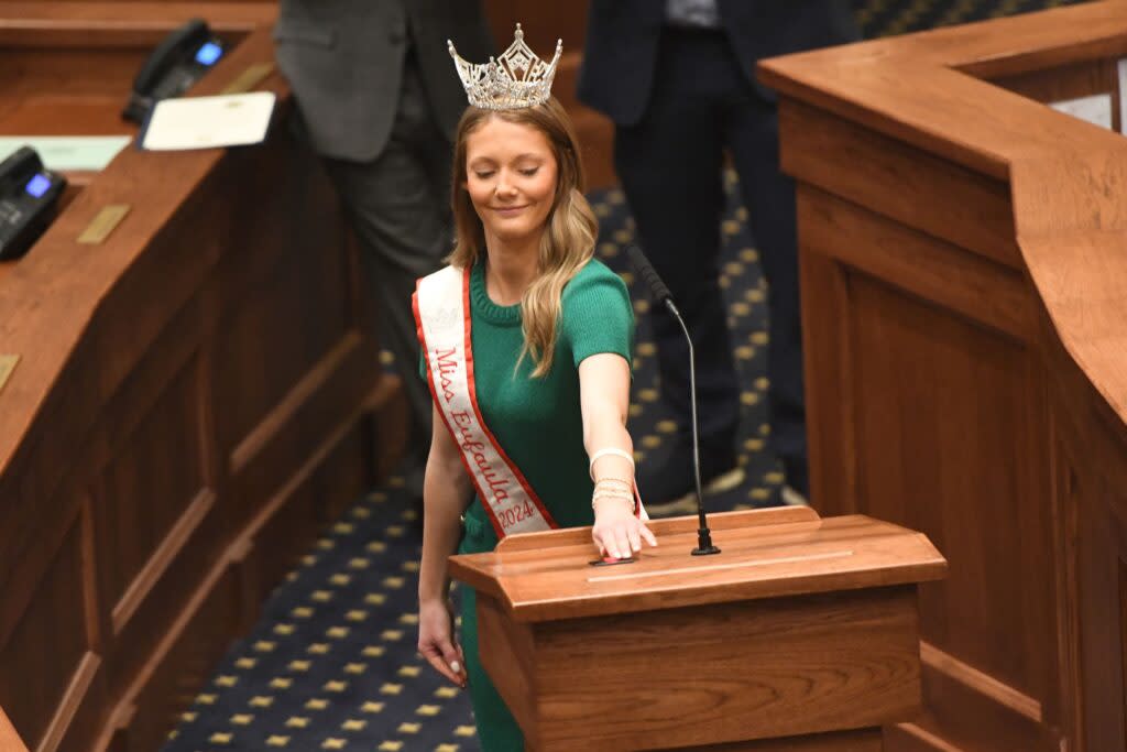 A woman wearing a crown turning off a microphone