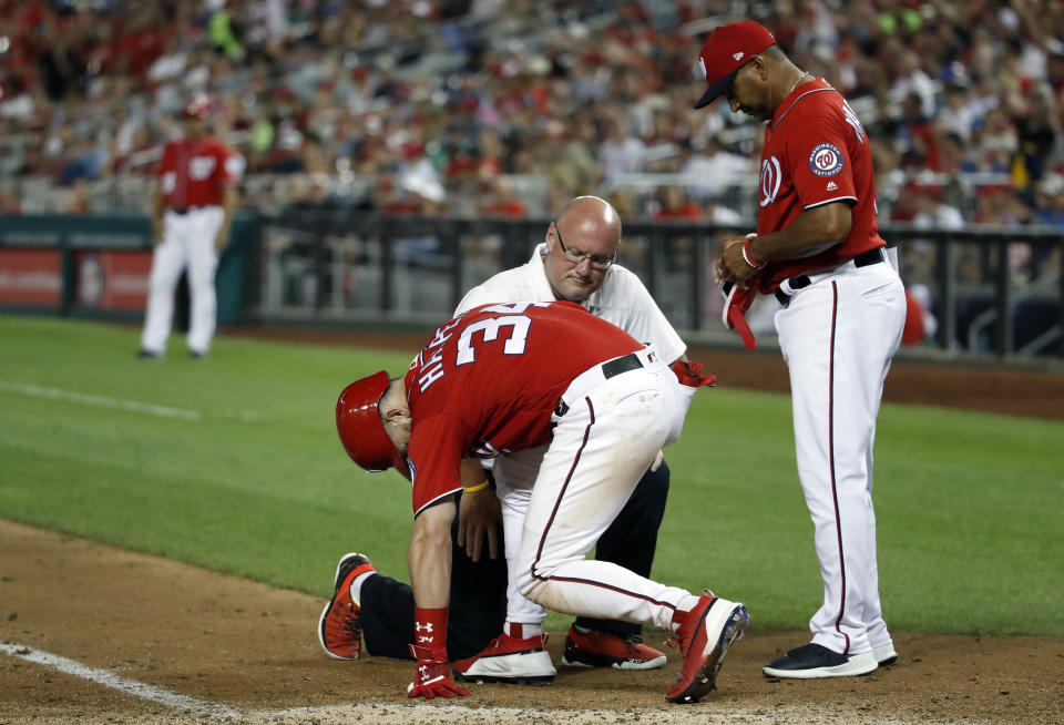 Washington Nationals' Bryce Harper is checked by trainer Paul Lessard and manager Dave Martinez, right, after he was hit by a pitch during the sixth inning of the second baseball game of the team's doubleheader against the Cincinnati Reds at Nationals Park, Saturday, Aug. 4, 2018, in Washington. (AP Photo/Alex Brandon)