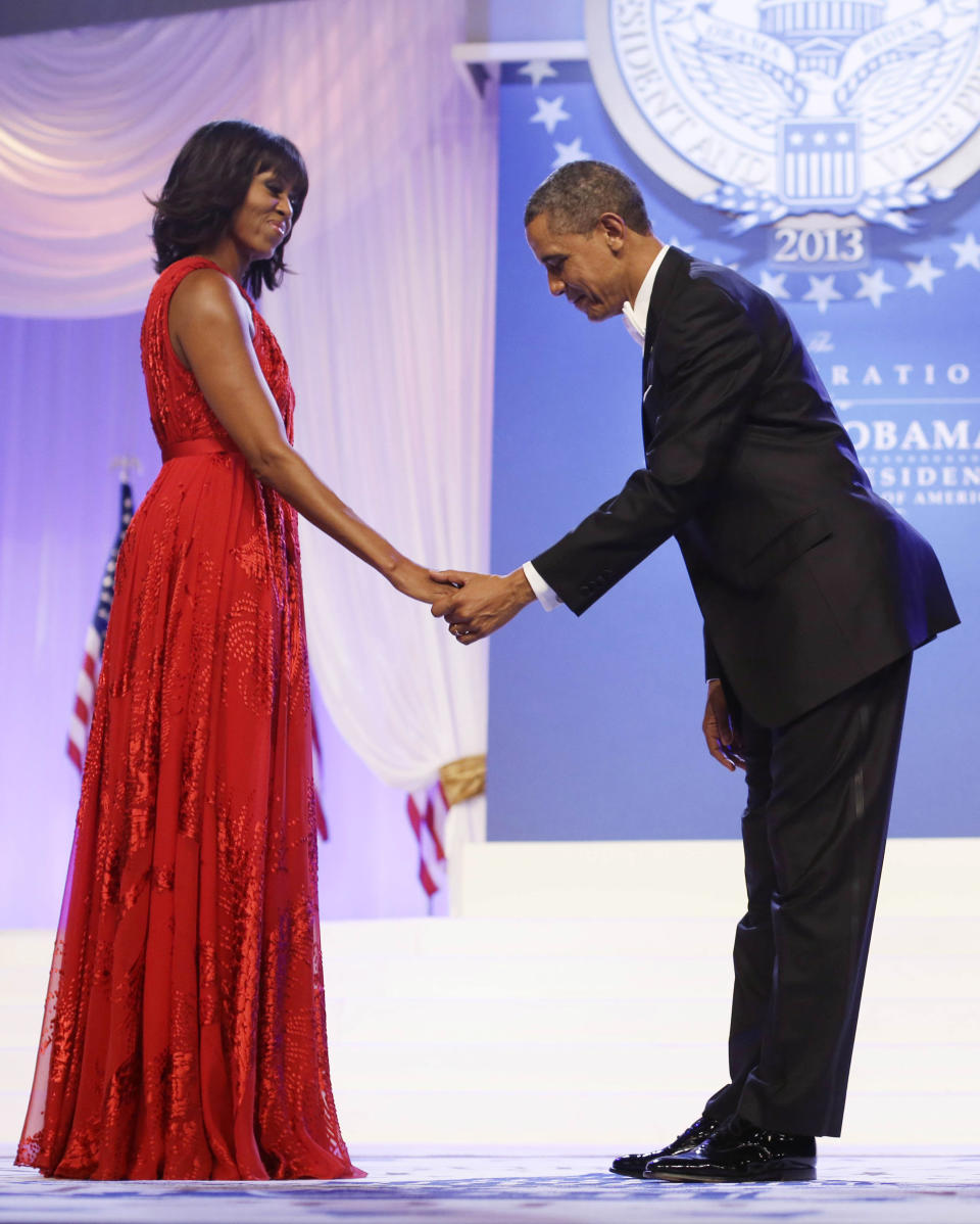 FILE - In this Jan. 21, 2013 file photo, President Barack Obama bows as he and first lady Michelle Obama, wearing a ruby-colored chiffon and velvet Jason Wu gown, gets ready to dance at the Inaugural Ball at the Washington Convention Center during the 57th Presidential Inauguration in Washington. Michelle Obama's fashion is making history again, at least for the next year, as her second inaugural gown will be displayed at the Smithsonian Institution. The ruby-colored chiffon gown made by designer Jason Wu is being lent to the National Museum of American History for a year to coincide with the 100th anniversary of the Smithsonian's first ladies exhibition. It will be paired with Obama's shoes designed by Jimmy Choo and will go on display beginning Tuesday, Jan. 14, 2014. (AP Photo/Charles Dharapak, File)