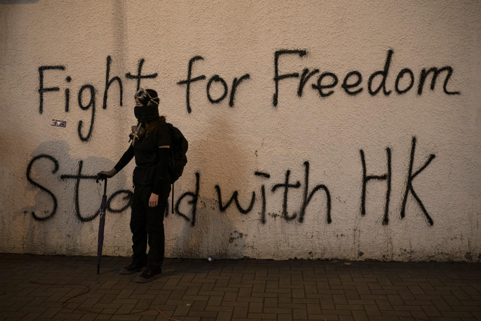 A black-clad protestor stands by graffiti on the wall in Hong Kong, Oct. 1, 2019. (Photo: Felipe Dana/AP)