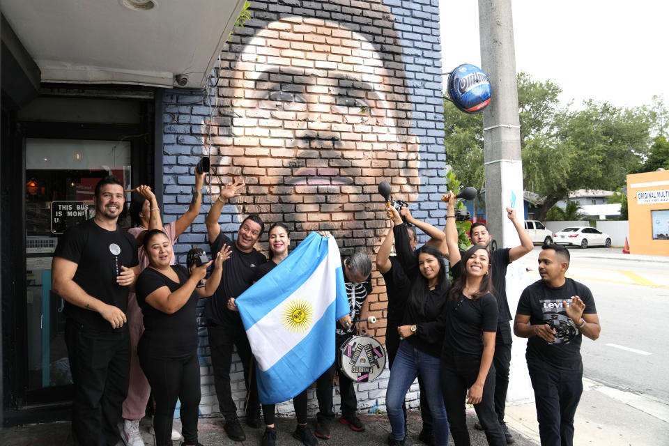 Trabajadores del restaurante Fiorito posan junto a un mural de Messi y la bandera argentina, en Miami. (AP Photo/Lynne Sladky)