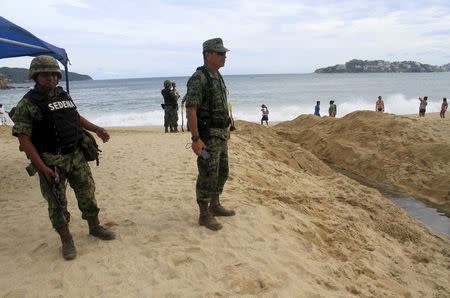 Soldiers keep watch at a beach as dark clouds brought by the proximity of tropical storm Carlos are seen in Acapulco, June 12, 2015. REUTERS/Claudio Vargas