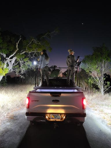 Amy Siewe and colleague standing in the back of a truck at night.