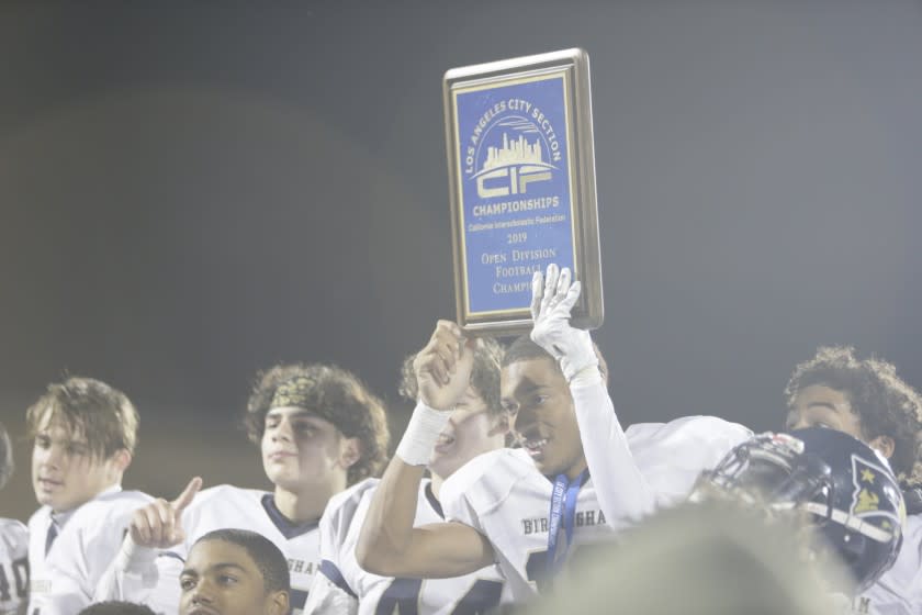 Los Angeles, CA., November, 29 2019: Mason White (19) hold the winning plaque as his team celebrates after their win over Banning. Banning High School and Birmingham High School face off in the City Section Open Division football championship game on Friday, November 29, 2019 at Car El Camino College. (Jason Armond / Los Angeles Times)