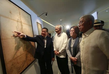 Philippines' Supreme Court associate justice Antonio Carpio (L) gestures to an ancient map on display while Philippines' Foreign Secretary Albert Del Rosario (2nd L), Justice Secretary Leila De Lima and Defense Secretary Voltaire Gazmin look on at a Catholic university in Manila September 11, 2014. REUTERS/Romeo Ranoco