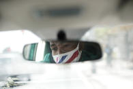 Diogo Jesus, the main dancer for the Mocidade Independente de Padre Miguel samba school, is rfelected in a rearview mirror of his car his, in Rio de Janeiro, Brazil, Thursday, Sept. 17, 2020. Jesus, who is referred to as “master of ceremonies” in the school, could no longer make rent without his income from dancing at private events and has started driving for Uber and sewing protective face masks to sell at a fair to make ends meet. Rio de Janeiro on Thursday, Sept. 24, said it has delayed its annual Carnival parade, saying the global spectacle cannot go ahead in February because of Brazil’s continued vulnerability to the new coronavirus pandemic. (AP Photo/Silvia Izquierdo)